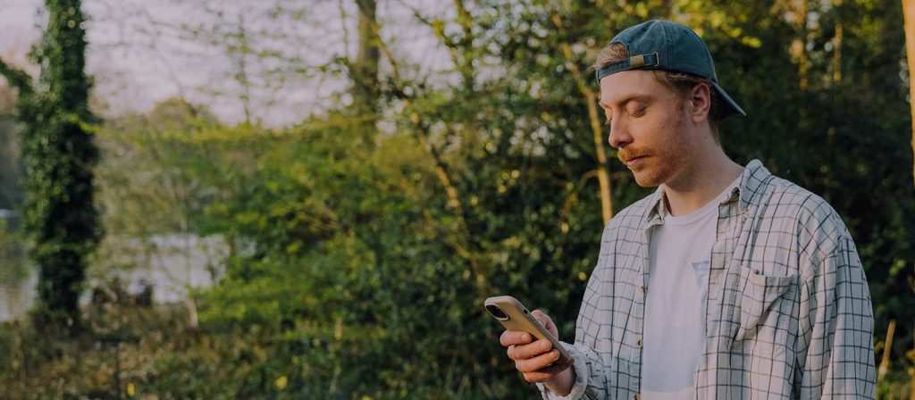 Young man outside practicing Lectio Divina using the Lectio 365 app on his phone
